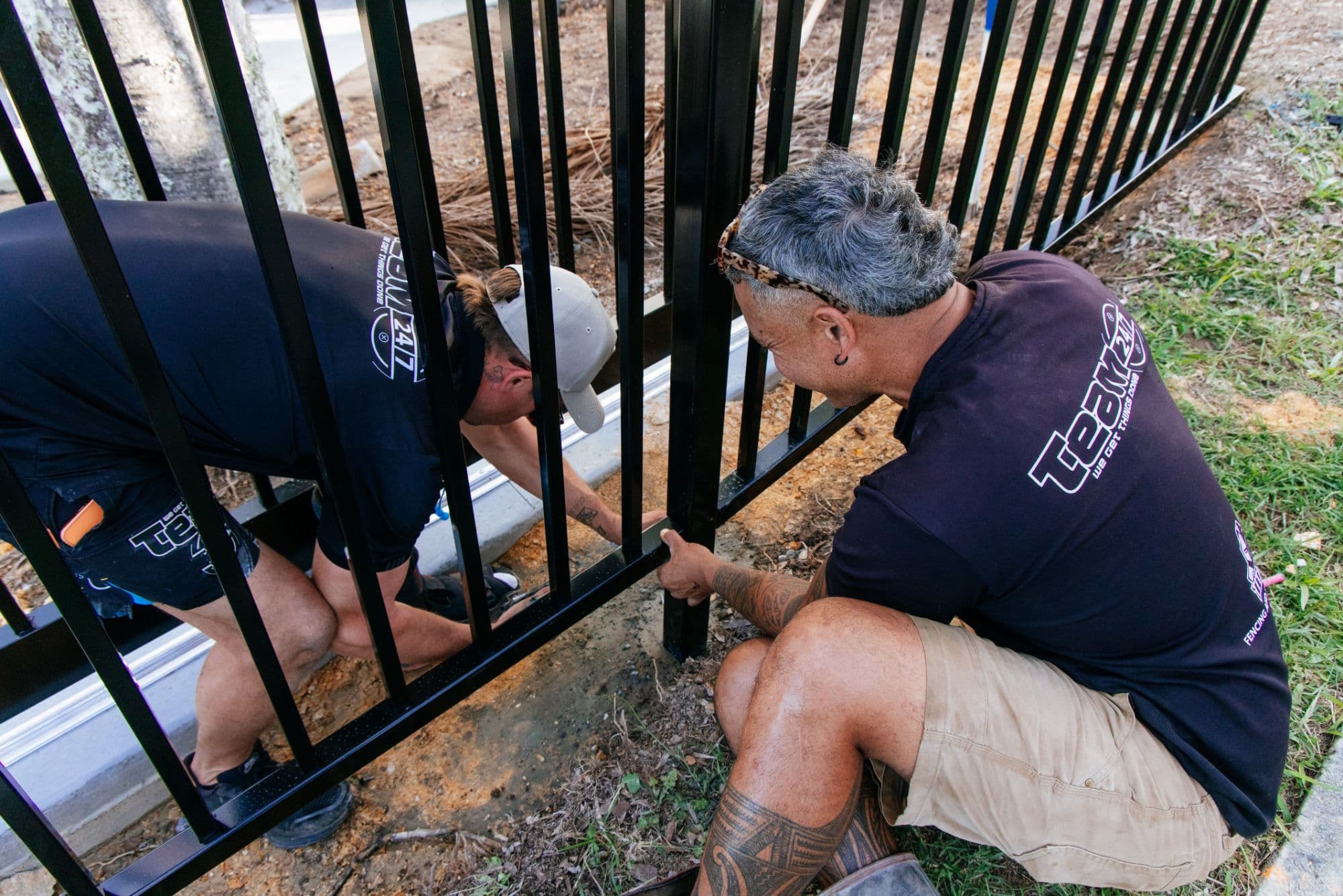 Team 247 crew installing a black steel commercial fence
